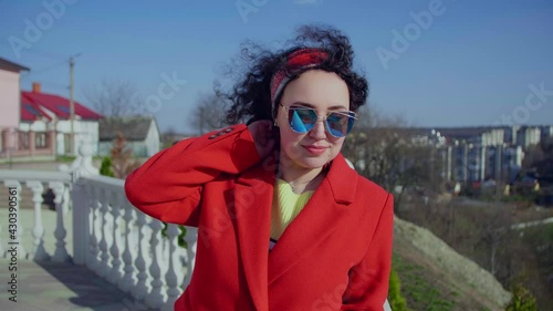 Pretty smiling curly woman in stylish look confidently sunglasses