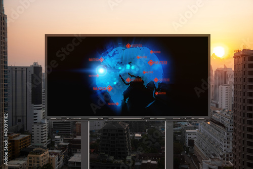Glowing hologram of Earth planet map on billboard over aerial panoramic cityscape of Bangkok at sunset. The concept of international business in Southeast Asia.