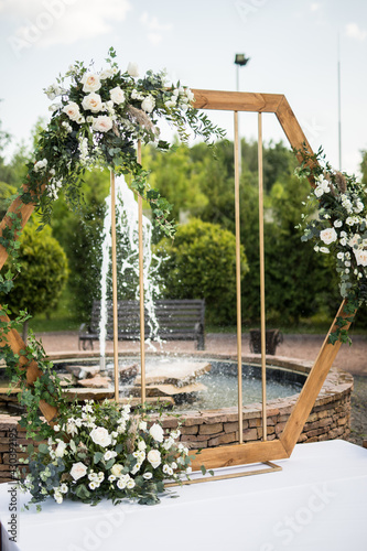 Vertical photo of wedding ceremony with arch in rustic style with fresh flowers