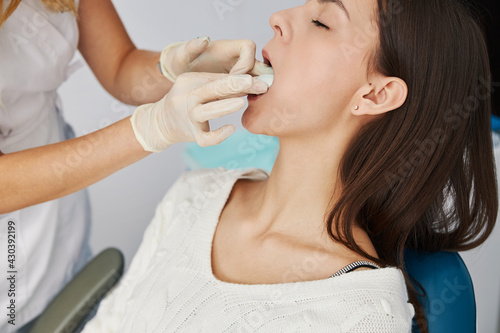 Dentist adjusting jaw cast putty lying on female tongue