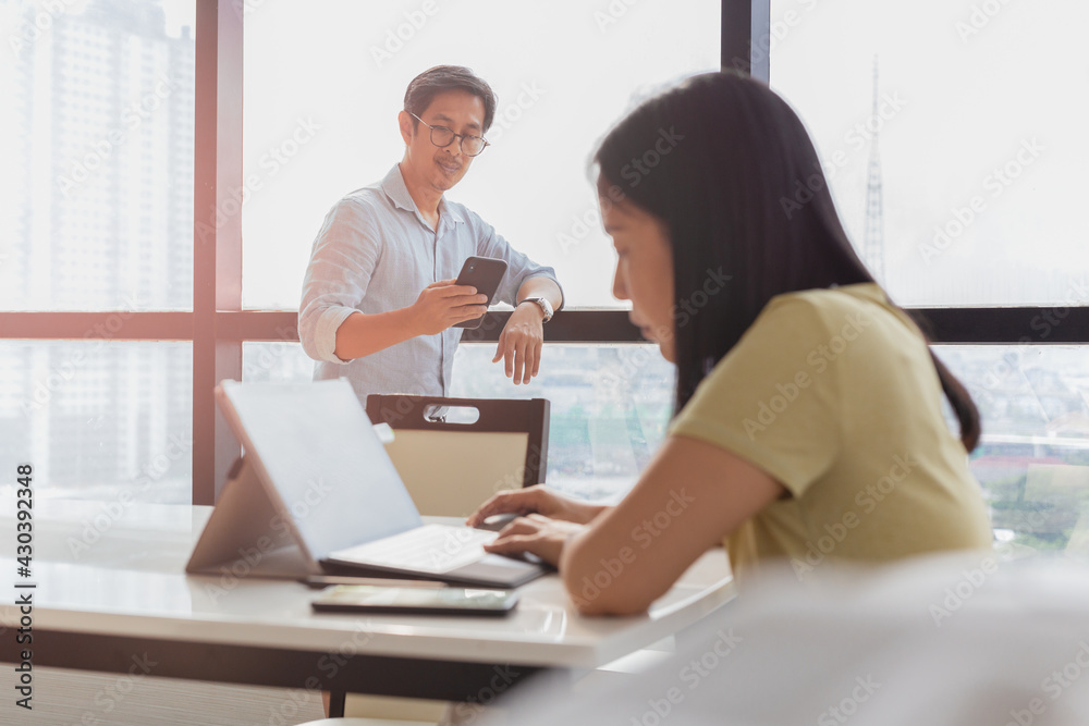 Businessman using cell phone with woman working on laptop in foreground. Businessman using cell phone with woman working on laptop in foreground.