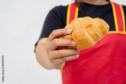 The croissant in hand is wearing a red apron with white background.