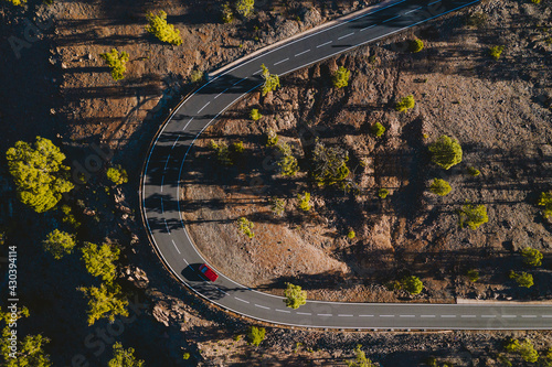 Aerial view of red vehicle driving on curvy mountain road in Tenerife, Canary islands, Spain. photo