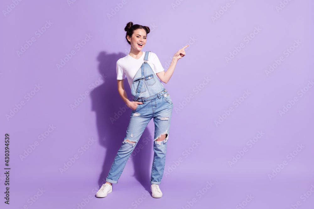 Full size portrait of pretty cheerful girl hand in pocket indicate finger empty space isolated on purple color background