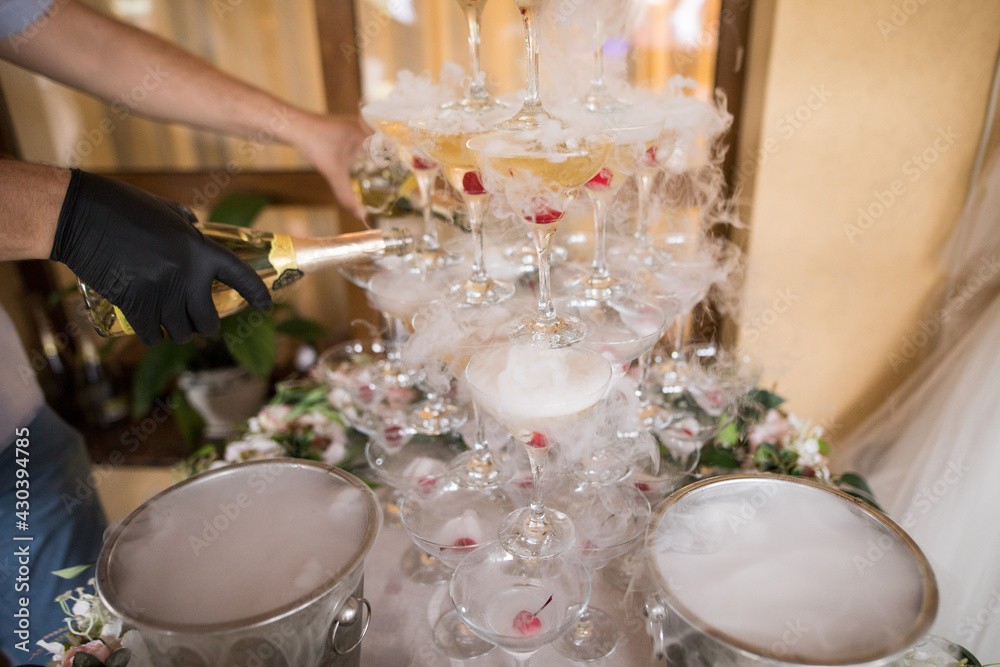 Horizontal photo of a hand that pours champagne into a wedding fountain
