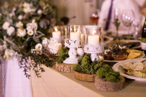 The presidium with floral arrangement with fresh white rose, wooden small circles with moss and fashion white candles