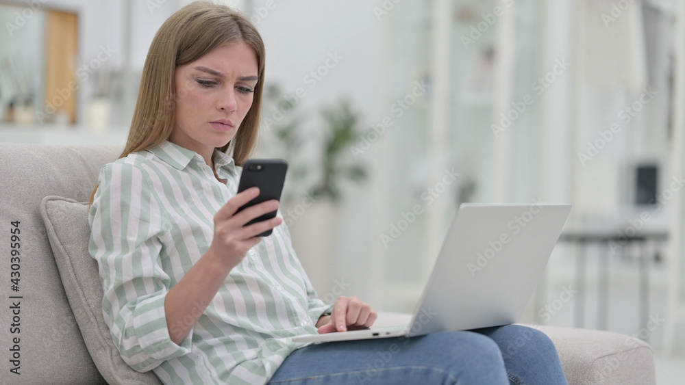 Young Woman using Smartphone and Laptop at Home Young Woman using Smartphone and Laptop at Home
