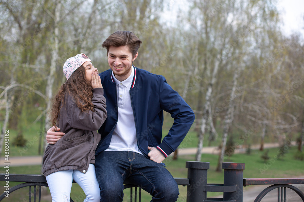 Fototapeta premium Little sister telling something funny to her older brother