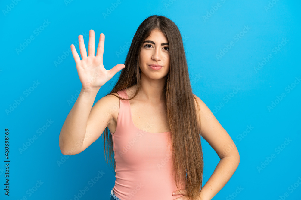 Fototapeta premium Young caucasian woman isolated on blue background counting five with fingers