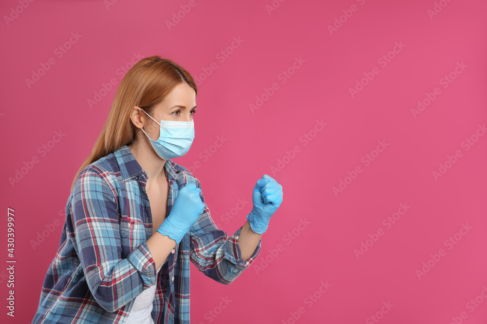 Woman with protective mask and gloves in fighting pose on pink background, space for text. Strong immunity concept Woman with protective mask and gloves in fighting pose on pink background, space for text. Strong immunity concept
