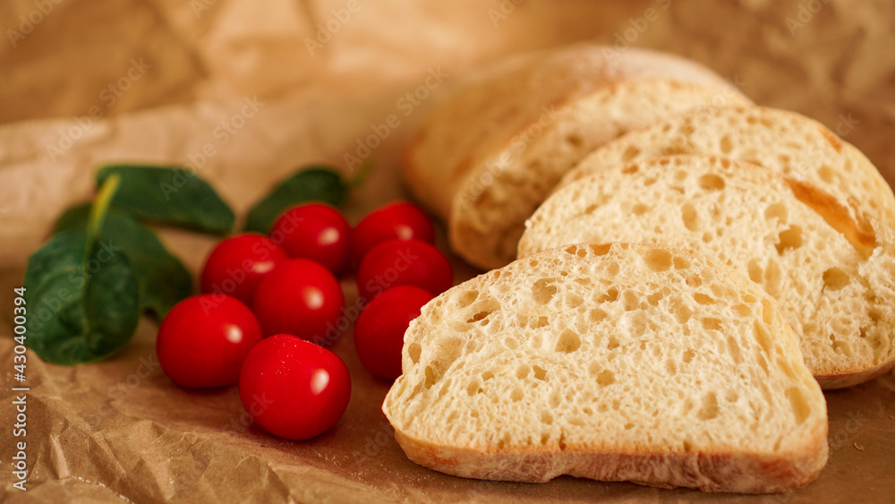 Ciabatta slices and cherry tomatoes on craft paper. Ciabatta slices and cherry tomatoes on craft paper.