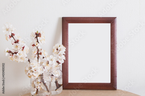 Photo frame mock-up on a table with flowering branches in a white interior