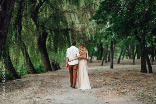 a guy and a girl are walking along the banks of a wild river overgrow