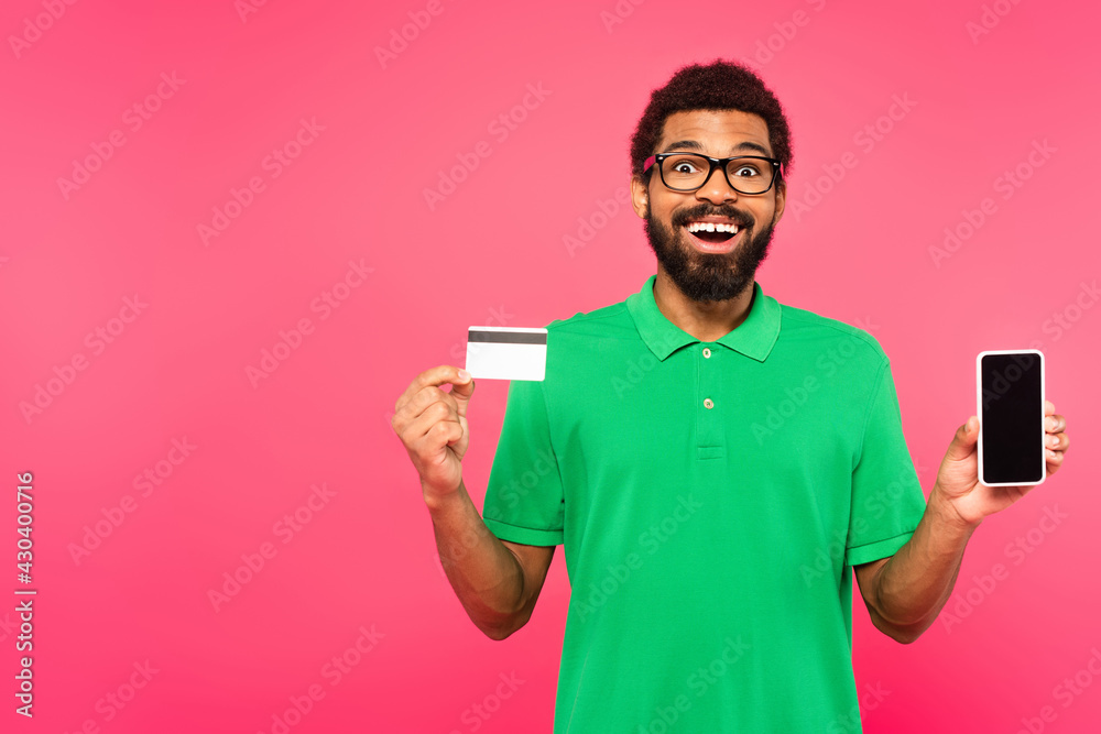 amazed african american man in glasses holding smartphone and credit card isolated on pink amazed african american man in glasses holding smartphone and credit card isolated on pink