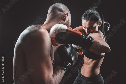 Shirtless Woman exercising with trainer at boxing and self defen