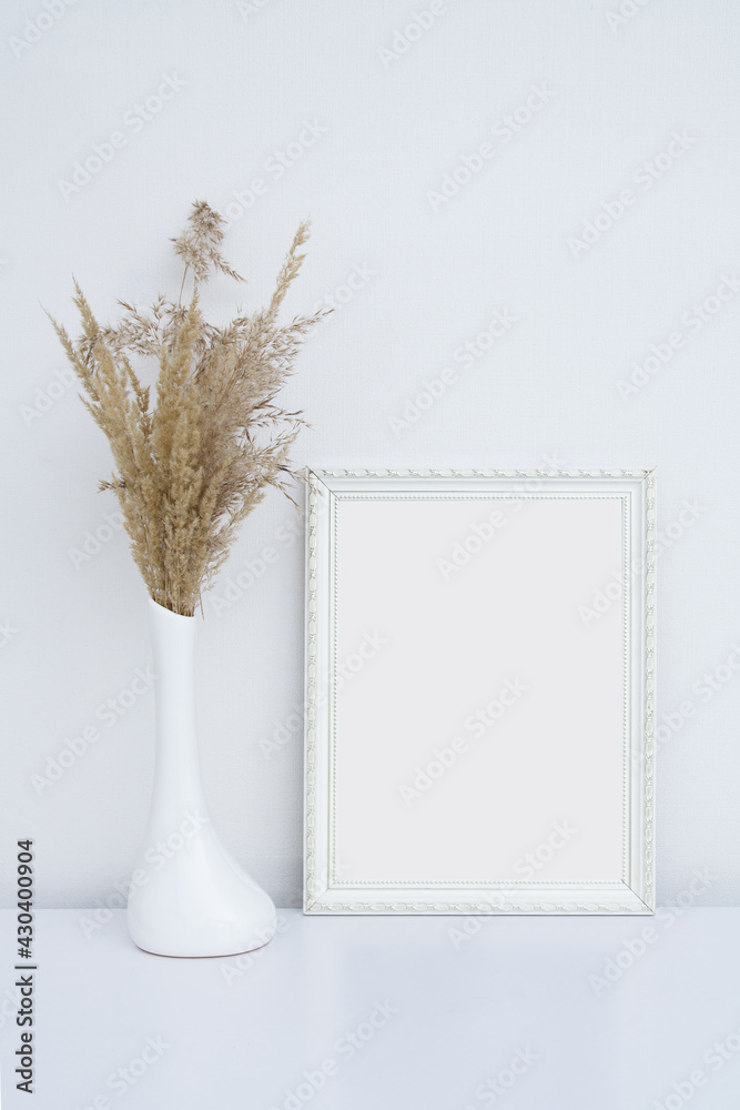 White photo frame mockup in white interior with vase and pampas grass