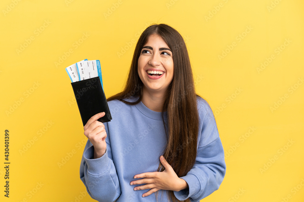 Young caucasian woman holding a passport isolated on yellow background smiling a lot Young caucasian woman holding a passport isolated on yellow background smiling a lot