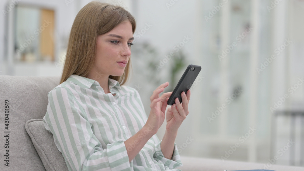 Serious Young Woman using Smartphone at Home 