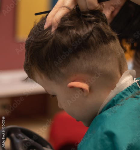 Little boy in the barbershop machine haircut.