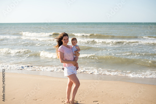 Happy family mother and baby resting at beach in summer