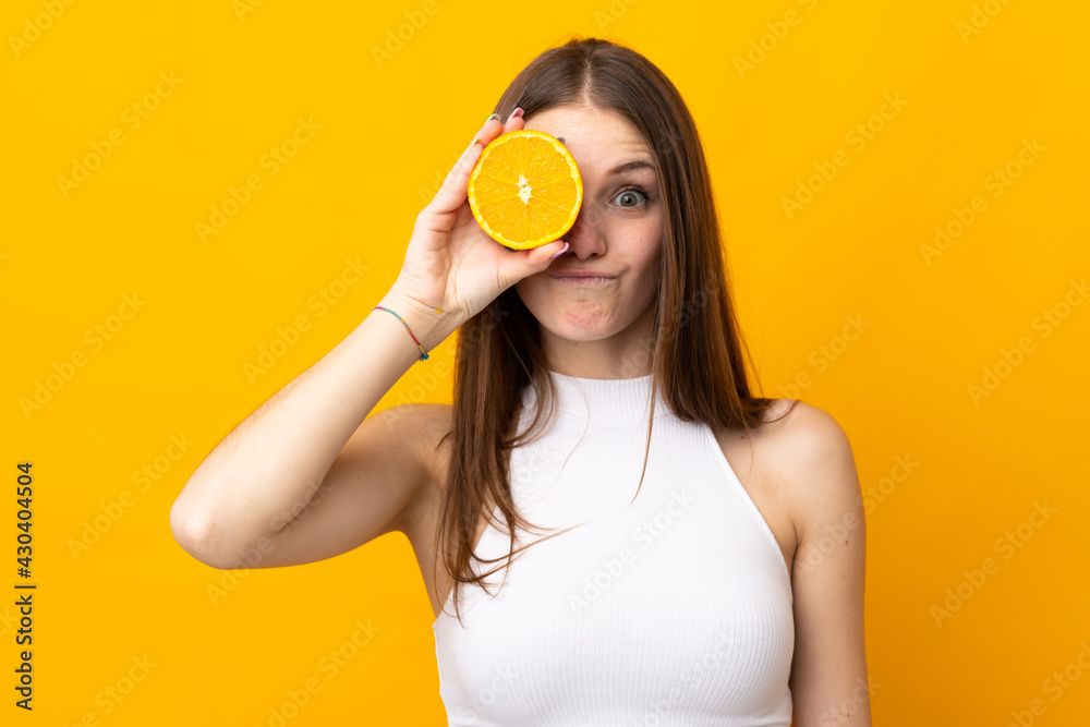 Young caucasian woman holding an orange isolated on orange background Young caucasian woman holding an orange isolated on orange background