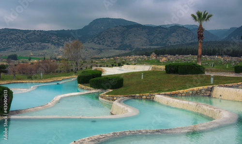 Artificial travertines in Pamukkale, Turkey with blue mineral water on a background of mountains