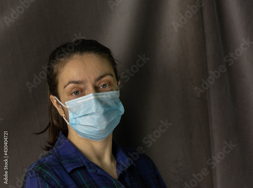 Portrait of a pretty white woman in a protective medical face mask due to a viral infection, health care, dark gray background photo