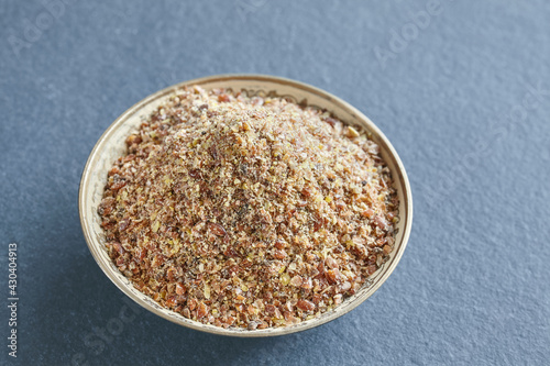 Ground flaxseed in a bowl on a slate background, selective focus.