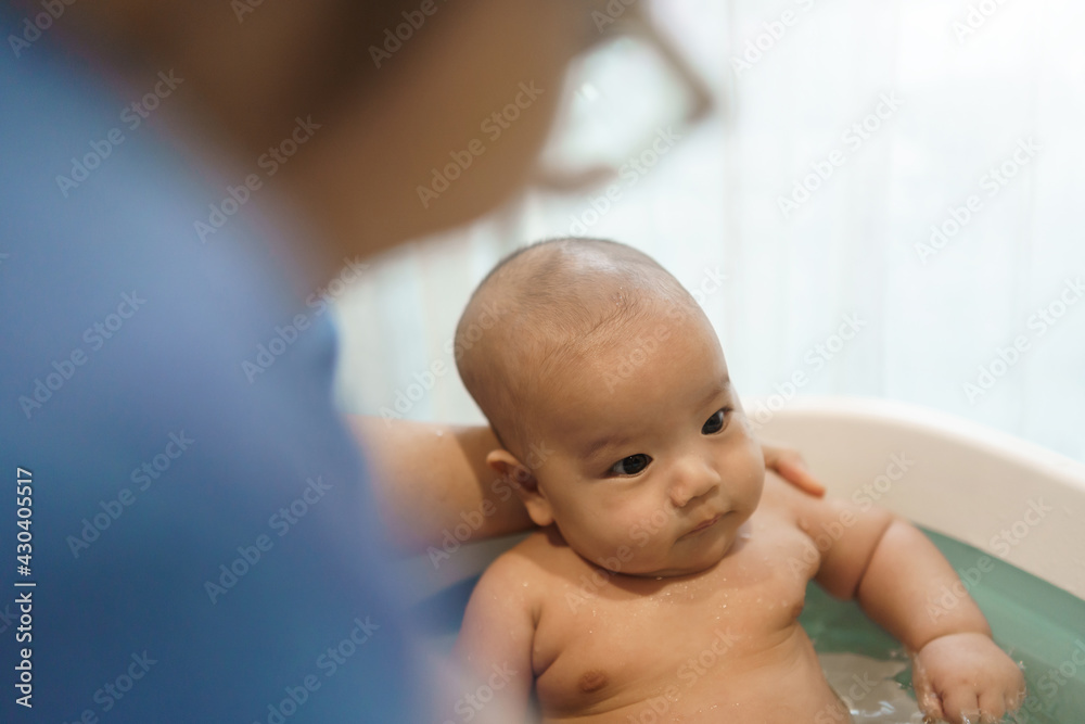 Asian Mother bathing her little baby boy in Bathtub at home. Asian Mother bathing her little baby boy in Bathtub at home.