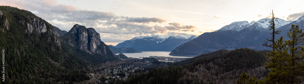 Squamish, North of Vancouver, British Columbia, Canada. Panoramic View from the top of the Mount Crumpit of a small town surrounded by Canadian Mountain Landscape. Spring Sunset
