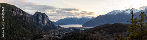 Squamish, North of Vancouver, British Columbia, Canada. Panoramic View from the top of the Mount Crumpit of a small town surrounded by Canadian Mountain Landscape. Spring Sunset