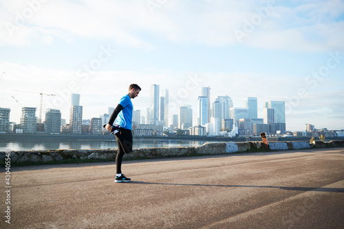 UK, London, Jogger stretching with downtown skyline in background