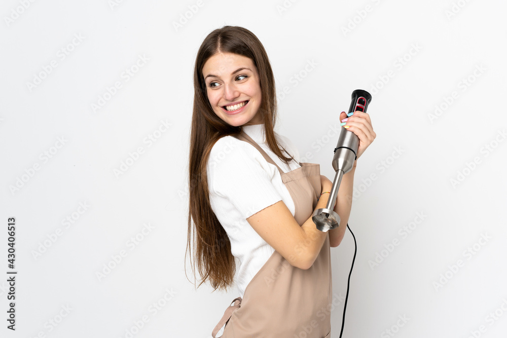 Young woman using hand blender isolated on white background laughing
