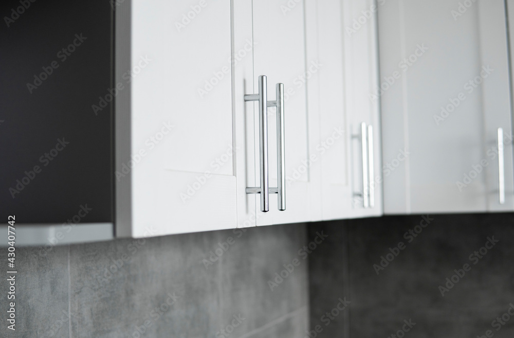 Modern minimalism style kitchen interior in monochrome tones. Custom kitchen with grey white facadesmdf and dark grey countertop with installed kitchen hood and sink. Modular kitchen from chipboard.