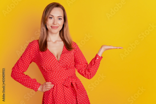 Young caucasian woman isolated yellow background holding copyspace on palm hand hip