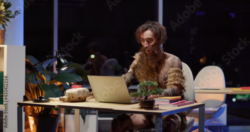Prehistoric young furry human entering office opening laptop getting scared. Savage receiving job working in the modern company. Humor concept.