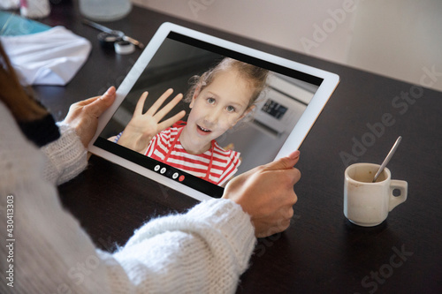 Video chiamata tra un adulto e una bambina che si salutano attraverso un tablet in contesto casalingo