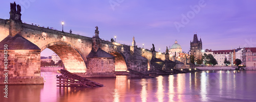 Banner, Charles Bridge in Prague on sunset. Panoramic image of Vltava riverside in purple, pink twilight with illuminated Charles Bridge, medieval towers. Famous travel destination in Czech Republic.
