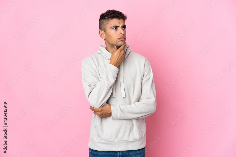 Young Brazilian man isolated on pink background having doubts Young Brazilian man isolated on pink background having doubts