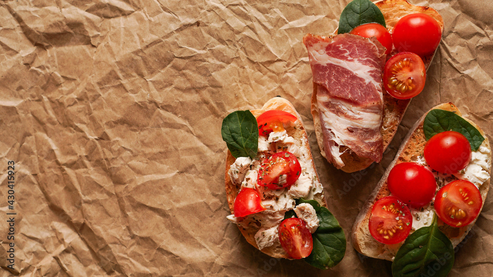 Three fresh bruschetta on craft paper. Delicious snack. View from above