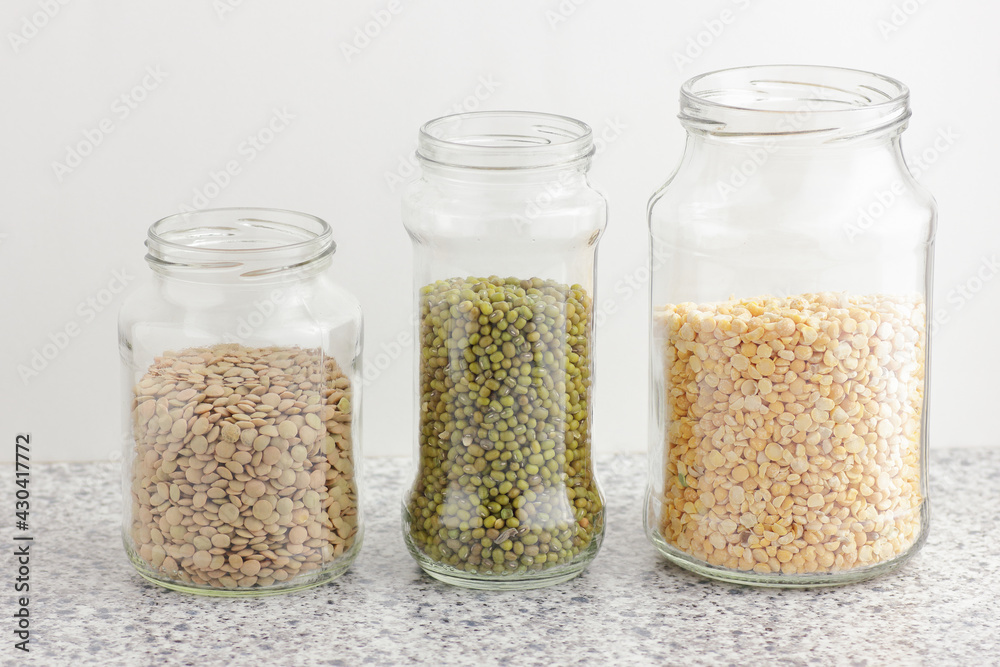 Variety of dry legumes: lentils, peas, green gram in glass jars uncooked on white kitchen background, zero waste, eco friendly, balanced diet food, healthy clean eating, vegan protein concept Variety of dry legumes: lentils, peas, green gram in glass jars uncooked on white kitchen background, zero waste, eco friendly, balanced diet food, healthy clean eating, vegan protein concept
