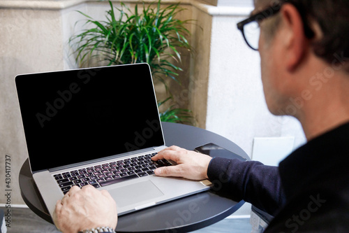 Dettaglio di un computer davanti al quale un uomo lavora  seduto alla scrivania di un ufficio photo