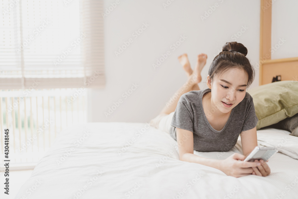 happy Young asian woman holding cellphone in bed happy Young asian woman holding cellphone in bed