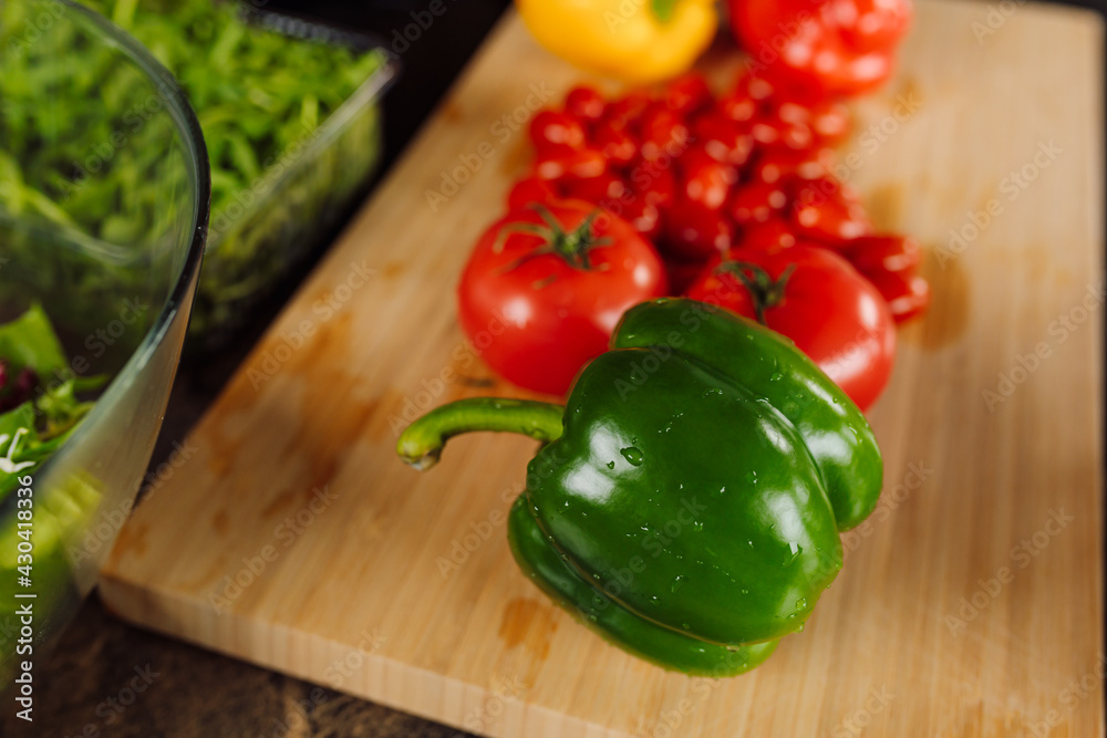 Foreground. Wooden cutting board, lies green pepper. Fresh ingredients for salad. healthy and proper nutrition concept. vegetarian food Foreground. Wooden cutting board, lies green pepper. Fresh ingredients for salad. healthy and proper nutrition concept. vegetarian food