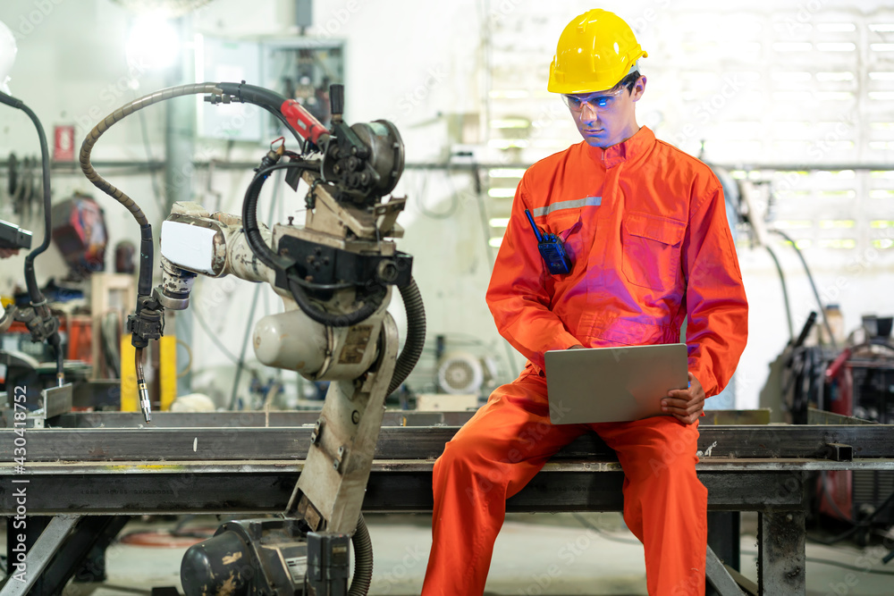 Factory 4.0 concept: Male engineer use laptop setting industrial robot in factiry Factory 4.0 concept: Male engineer use laptop setting industrial robot in factiry