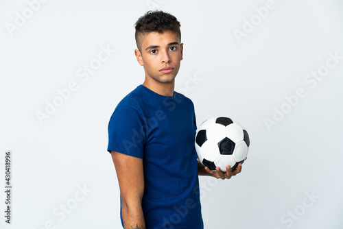 Young Brazilian man over isolated background with soccer ball