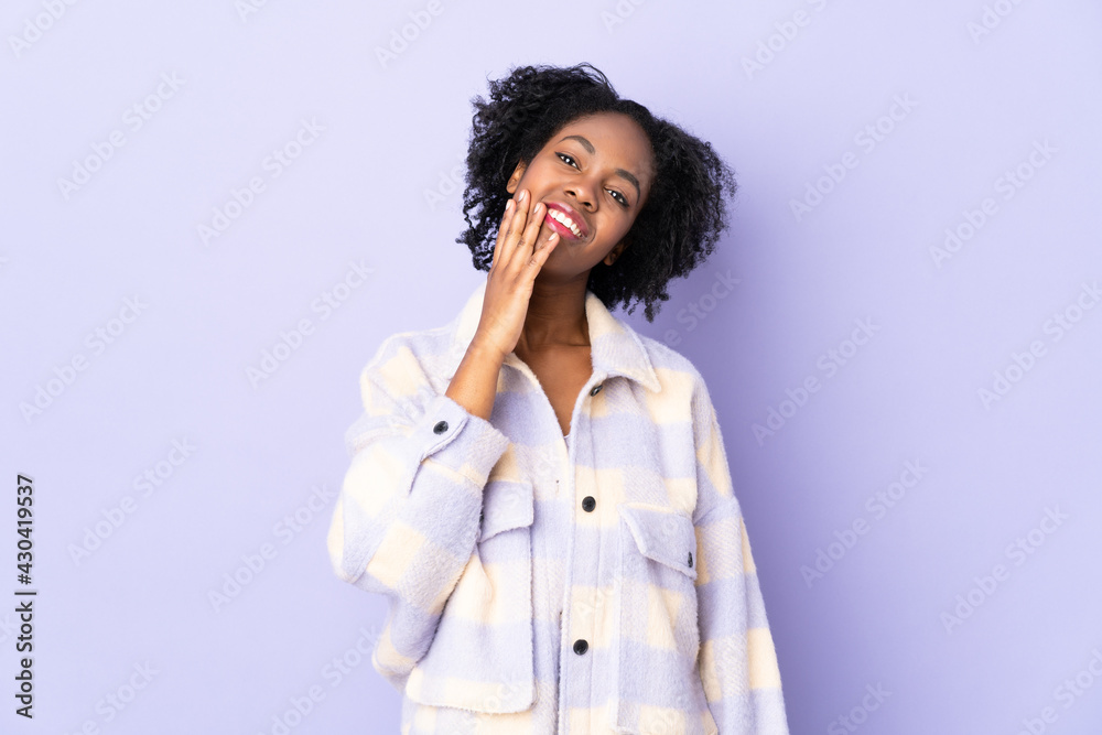Young African American woman isolated on purple background looking up while smiling
