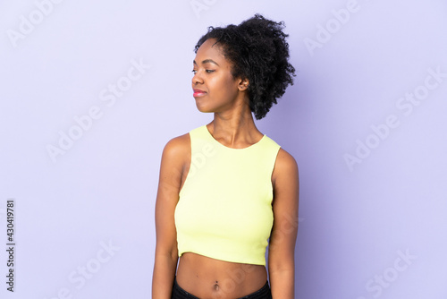 Young African American woman isolated on purple background looking to the side