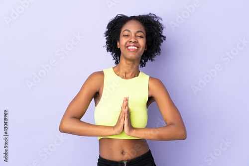 Young African American woman isolated on purple background keeps palm together. Person asks for something © luismolinero