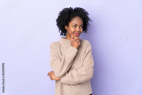Young African American woman isolated on purple background thinking an idea while looking up © luismolinero